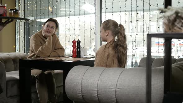 the Waiter Brought Food to the Family Sitting at the Table in the Cafe alt