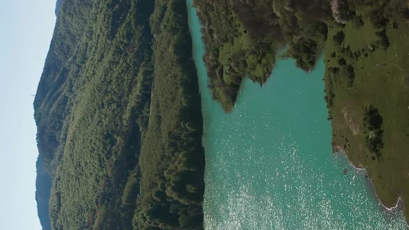 Sunlight glistens off surface of Maneciu Dam lake, Romania. Vertical aerial pan alt