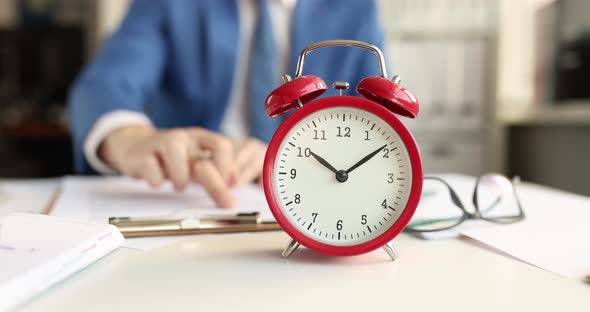Red Classic Alarm Clock Standing in Front of Businessman Studying Documents  Movie alt