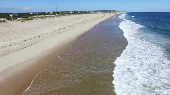 Aerial pan of waves crashing on beach alt