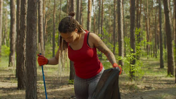 Woman Volunteer Collecting Trash Into Garbage Bag alt