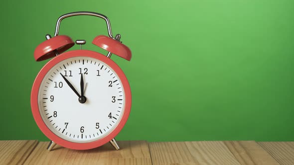 Vintage Red Alarm Clock on a Natural Wooden Table Ringing at 12 O'clock