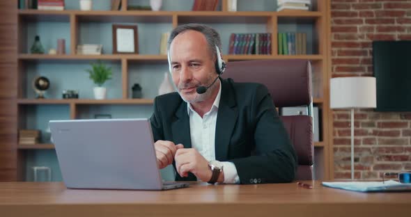Businessman in Headset Holding Videochat on Computer with His Business Partners in Modern Office alt