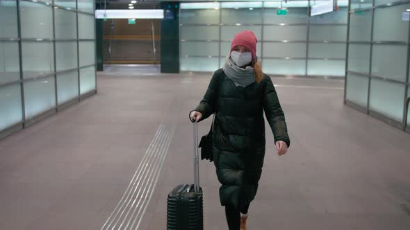 Woman in Mask Walks with Suitcase in Airport. Coronavirus Pandemic Travel Ban