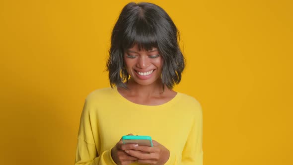 Cheerful Overjoyed Dark Skinned Woman Reads Social Network News or Funny Story alt