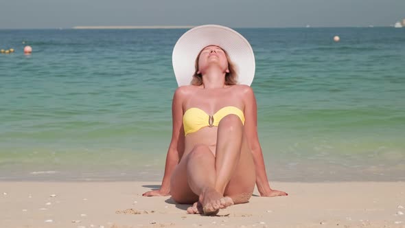 Attractive Sexy Woman is Sunbathing on a Sandy Beach and Taking a Sun Bath