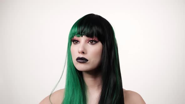 Portrait of Caucasian joyful stylish woman in black-green wig on lifht background alt