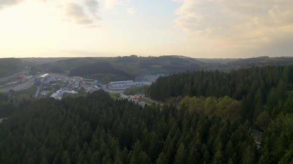 Aerial view descending above woodland to Circuit De Spa-Francochamps racetrack Stavelot Belgium alt