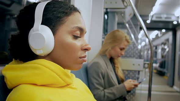 Young Woman Listening Music in Modern Metro Train Wearing Headphones alt