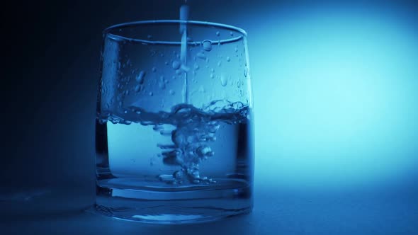 An effervescent soluble tablet falls into a glass of water. On a blue background alt