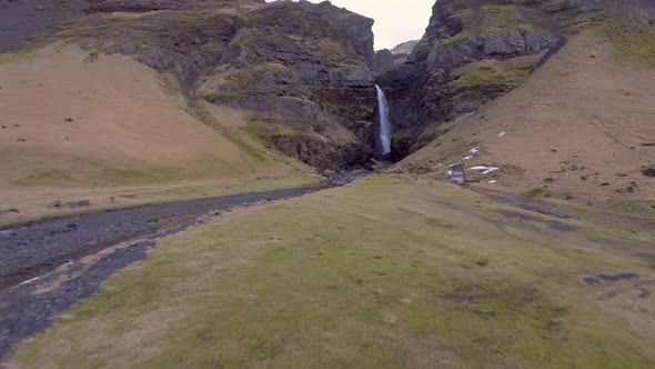 Aerial view of waterfall in Iceland with snowy mountains on background