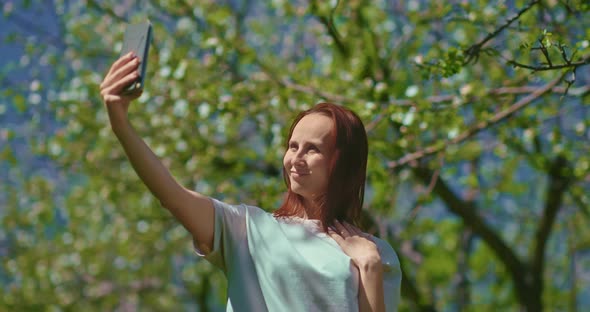 Joyful Woman is Taking Selfie By Mobile Phone in Blooming Garden  Prores