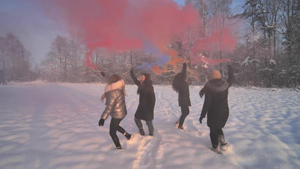 Girls Friends Run Across the Winter Field with Colored Smoke alt