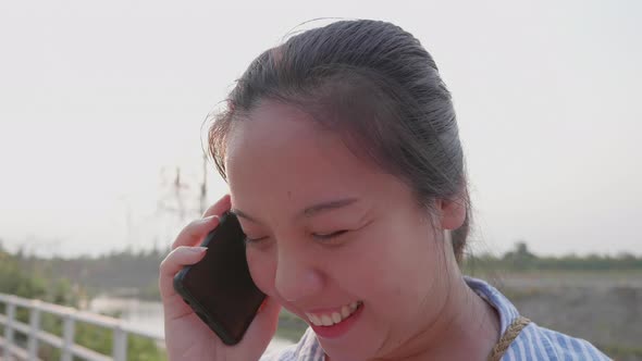 Asian short hair woman laughing with smartphone call to friend at outdoor alt