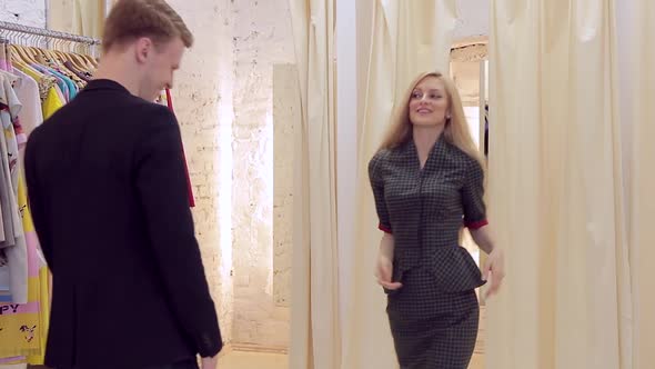 A Woman in a Store Tries on a Checkered Suit That a Man Likes alt
