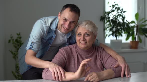 Head Shot Happy Young Bearded Man Embracing Beautiful Smiling Middle Aged Senior Mother in Eyewear alt