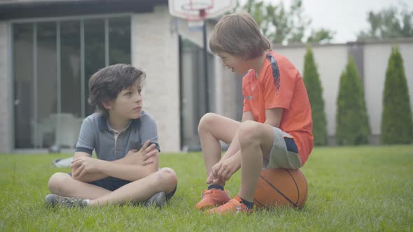 Excited Little Boy Sitting on Ball and Talking with Friend. Portrait of Two Happy Caucasian Children alt