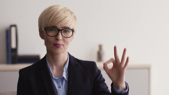 Close Up Portrait of Optimistic Middle Aged Businesswoman in Glasses Smiling to Camera and Gesturing alt