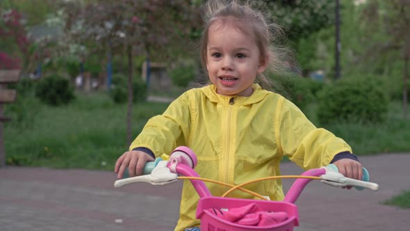Authentic Cute Little Preschool Baby Girl in Yellow Pink Riding a Bike in Park Crawling on Grass at