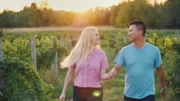 Happy Multiethnic Couple Walking in the Vineyard. Wine Tasting and Tourism Concept alt