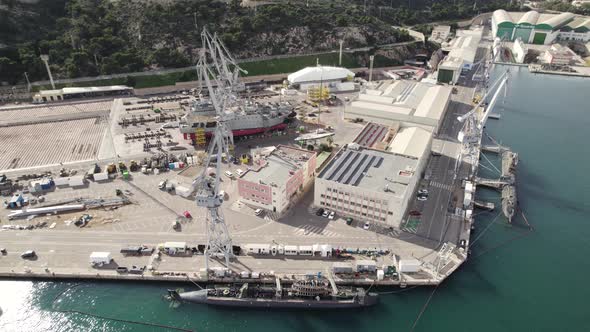 Aerial descend view over Cartagena naval base, ship and submarine on dock, Spain