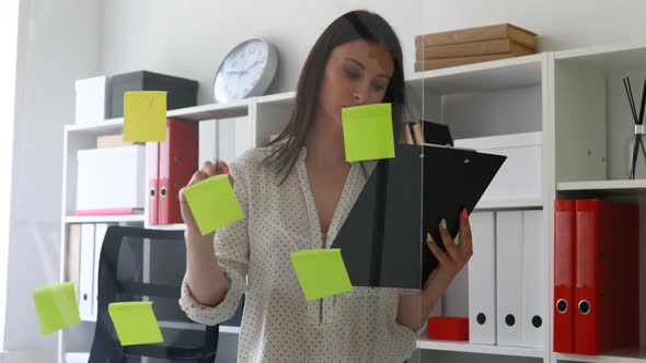 Businesswoman Marking Sticky Notes on Glass Wall
