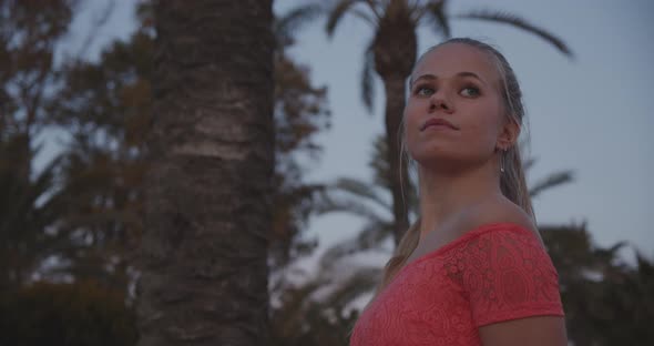 Model Posing Outdoors with Defocused View of Trees and Sky in Background alt