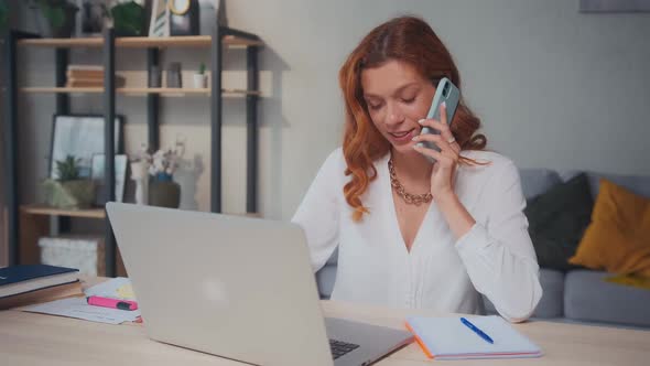 Woman Manager Works in Multitasking Mode Talking on Phone and Typing in Laptop alt