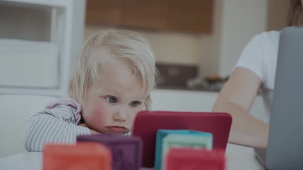 Adorable Toddler Child Looks Carefully at a Smartphone While Sitting at a Table alt