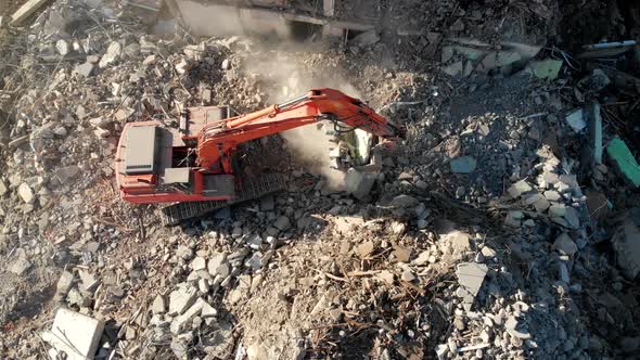 An Excavator Tractor Digs the Concrete Ruins of a Collapsed House with a Bucket