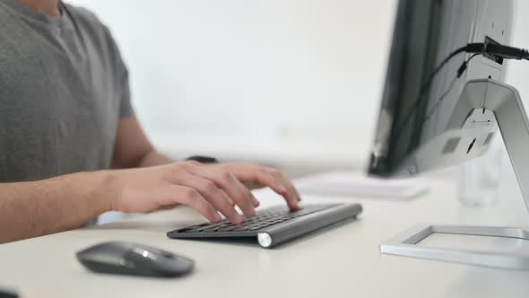 Hands of Young Man Typing on Keyboard Close Up alt