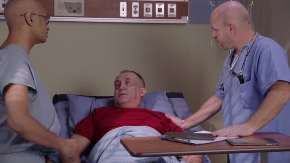 Senior man in hospital bed talks to doctors