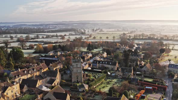 Aerial drone video of a Cotswolds Village, English countryside fields and scenery with houses, prope alt