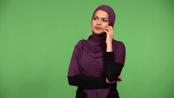 A Young Beautiful Muslim Woman Argues on a Smartphone  Green Screen Background