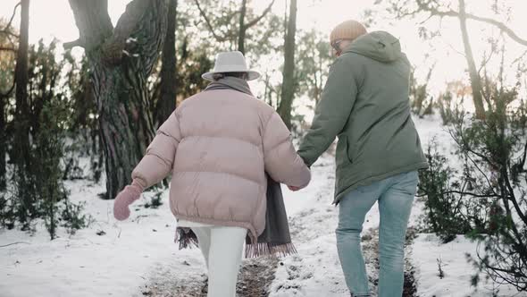 Romantic Couple Walks in the Woods Holding Hands on a Sunny Winter Day