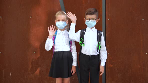 Schoolchildren in Masks with Backpacks Saying Hello During COVID 19 alt