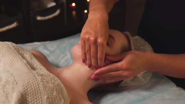 A Woman Enjoys a Massage of the Face and Neck