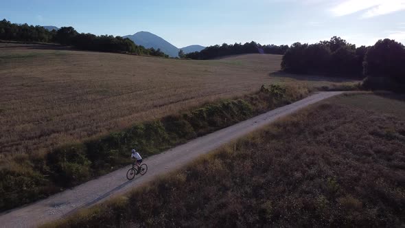 Biker riding on dust road, Marche, Italy alt