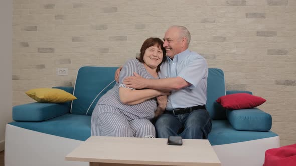 Senior Couple Sitting on Sofa and Talking About Their Happy Moments Together alt