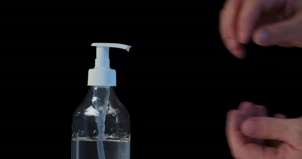 Man Push Dispenser and Liquid Soap Squeezed Out To Hand, Black Background.  alt