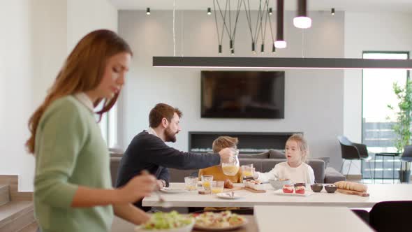 Young mother preparing breakfast for her family in the modern kitchen