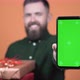 A man with gifts in his hands holds a phone with a green screen in front of him - VideoHive Item for Sale