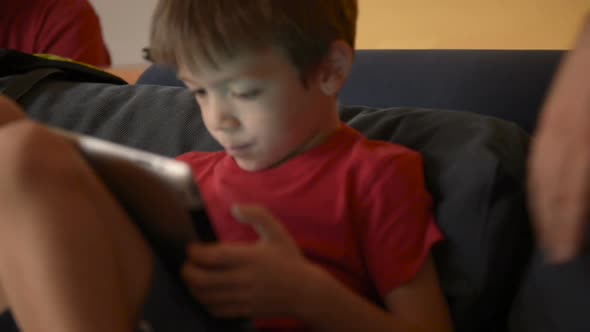 Child Play with Tablet on Sofa at Home with His Dad
