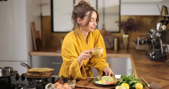 Woman Having a Breakfast on the Kitchen at Home alt