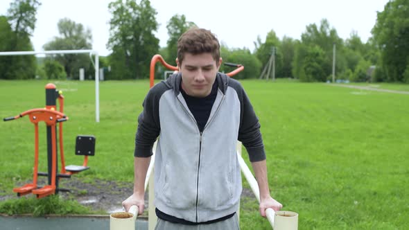 Teenager push ups on uneven bars, training in the fresh air alt