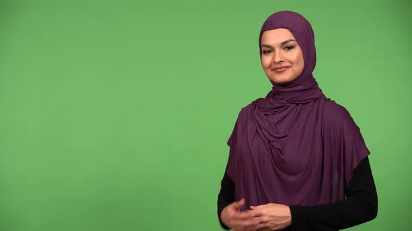 A Young Beautiful Muslim Woman Motions to the Camera in a Gesture of Invitation  Green Screen