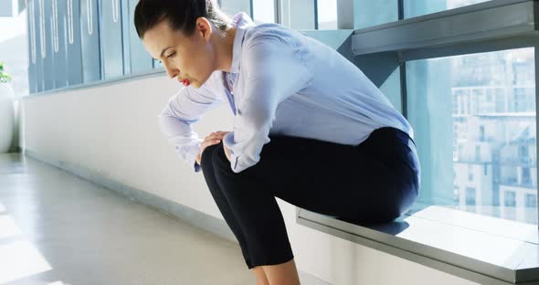 Tense female business executive sitting with hand on forehead alt