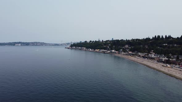 Drone shot revealing the Seattle skyline, including the Space Needle, from behind a hill near Alki b alt
