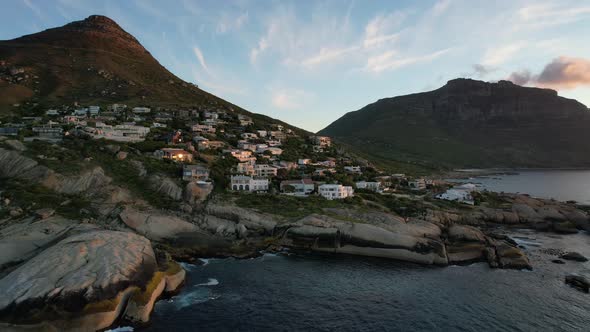 Expensive oceanfront mansions on mountain hill at Llandudno Beach in Cape Town, aerial alt