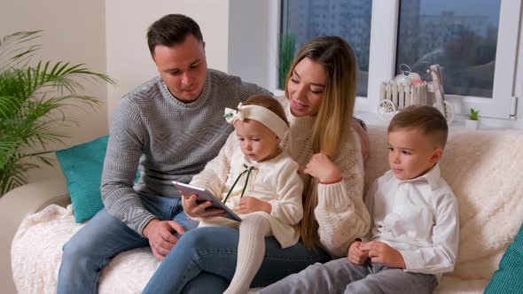 Family with Two Kids Speaking with Grandmother on Web Camera Making Hi Sign alt